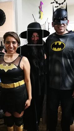 three people dressed up as batman and catwoman posing for a photo in their living room