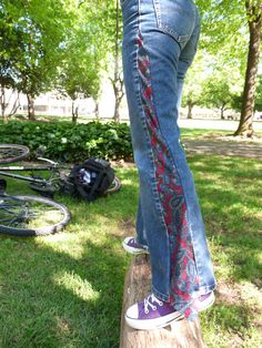 someone standing on top of a tree stump with their feet in the air and wearing jeans