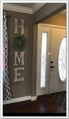 a door with the word home painted on it next to a wreath and window sill