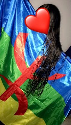 a woman with long hair is holding a colorful heart shaped kite in front of her face