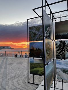 the sun is setting behind an art display with multiple pictures on it's sides