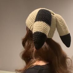 a woman with long hair wearing a crocheted hat in the shape of an animal