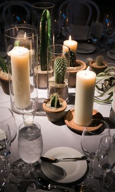 the table is set with candles, plates and succulents for dinner guests