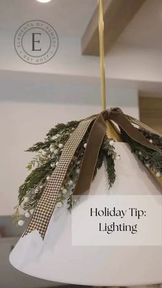 a white light fixture with a brown ribbon on it and the words holiday tip lighting above it