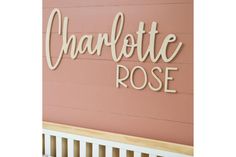 the sign for charlotte rose is hanging on the wall next to a bench in front of a pink painted wall