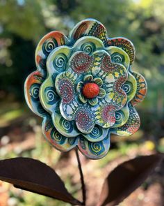 a flower made out of clay sitting on top of a plant