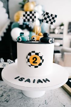 a white cake with black and yellow decorations on it's top that says 2 year