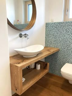 a bathroom with a sink, mirror and toilet in the corner next to a wooden shelf