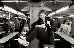 a black and white photo of a man sitting on a train