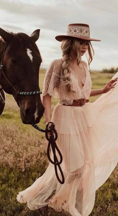 a woman in a dress and hat walking with a horse