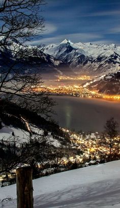 a view of the city lights in the distance from top of a mountain