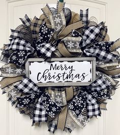 a black and white christmas wreath with the words merry christmas on it hanging from a door