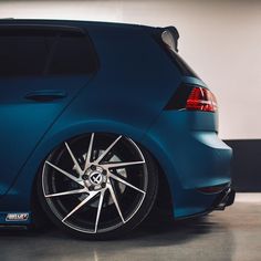 the back end of a blue car with chrome spokes on it's wheels