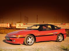 a red sports car parked in front of a train