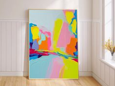 an abstract painting in bright colors on a wall next to a window with white waives