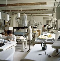 people working in a sewing factory with lots of white clothes on mannequins