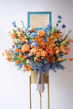 an orange and blue flower arrangement on a stand