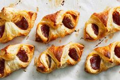 several pastries with pepperoni on them are lined up