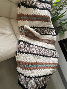 a crocheted blanket sitting on top of a couch next to a potted plant