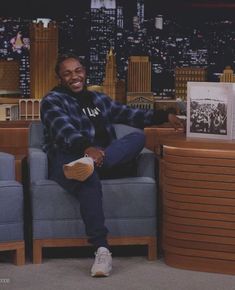 a man sitting on top of a blue couch in front of a table with an open book