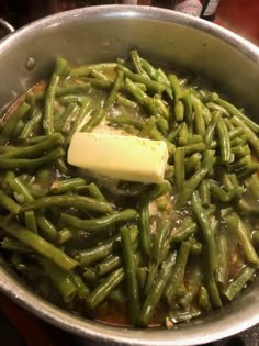 green beans are being cooked in a pot with butter on the top and some other ingredients