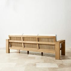 a wooden bench sitting on top of a tile floor next to a white wall in an empty room