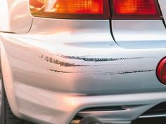 the back end of a white car with black marks on it's bumper and tail lights