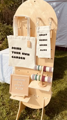 two tote bags are on display in front of a wooden stand with different types of thread