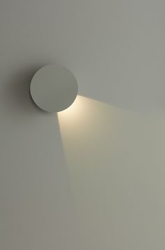 a round light fixture on the wall in a room with white walls and flooring