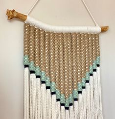 a wall hanging made out of macrame beads and wood with a wooden stick