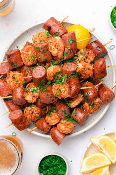 smoked sausage and shrimp skewers on a white plate with lemon wedges in the background