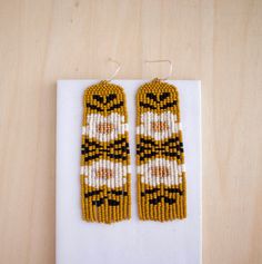 the beaded earrings are made with yellow and black seed beads, which is decorated with an image of a tiger