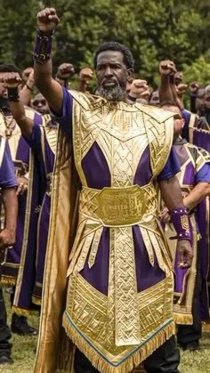 a group of men in gold and purple outfits standing next to each other with their hands up