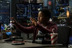 a man sitting at a desk with his hands up in front of the monitor screen