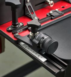 a close up view of a machine tool on a table with red and black trimmings