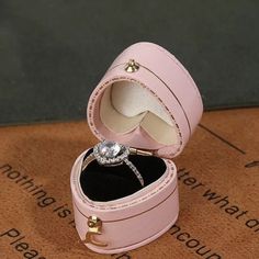 an open pink leather jewelry box with a diamond ring inside