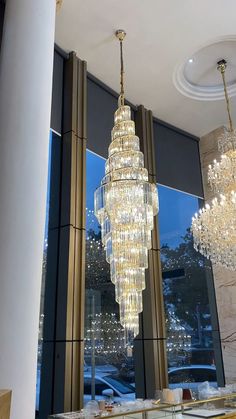 a large chandelier hanging from the ceiling in a room with tall columns and windows