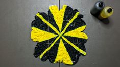 a yellow and black piece of art sitting on top of a metal surface next to a roll of tape