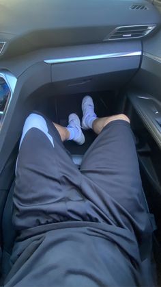 a person laying in the driver's seat of a car with their feet up