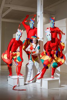 three people dressed in colorful costumes standing next to each other on white pedestals with red and yellow decorations