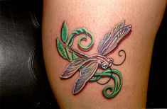 a tattoo on the leg of a woman with green and purple dragonflys painted on it