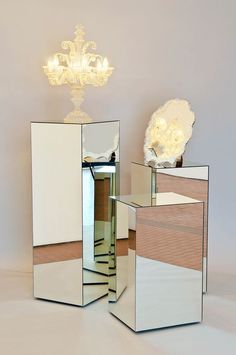 three mirrors sitting next to each other in front of a chandelier