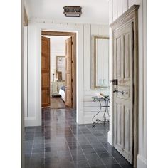 an open door leading to another room with white walls and black tile flooring on either side