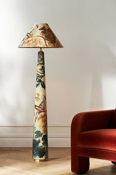 a lamp sitting on top of a wooden floor next to a red chair