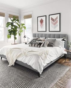 a bedroom with a bed, rug and two pictures on the wall above it that have plants in them