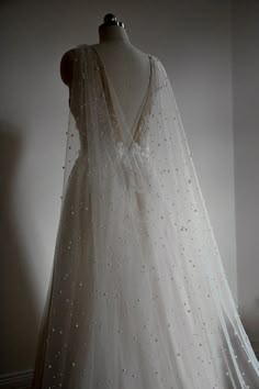 a white wedding dress on a mannequin in front of a wall and floor