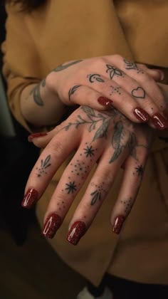 a woman's hands with tattoos and red nail polishes on them, holding onto her hand