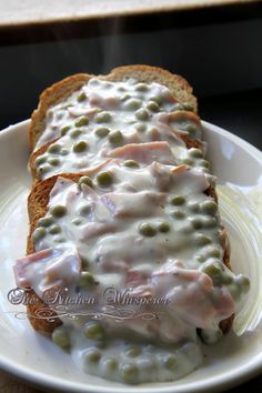 a white plate topped with two pieces of bread covered in cheese and peas