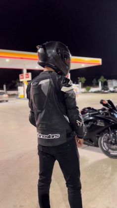 a man standing in front of a motorcycle at a gas station with his back to the camera