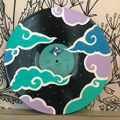 a vinyl record with an image of the sky and clouds painted on it's side